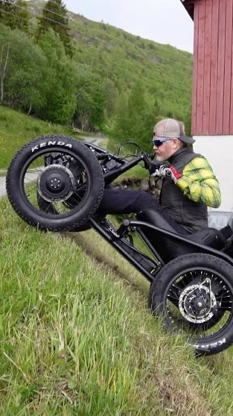 Mike Harrison riding an Exoquad up a steep grassy slope